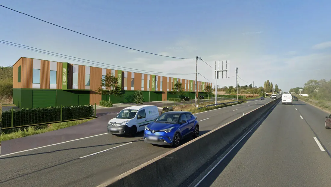 Perspective depuis la N20 : le bâtiment et ses enseignes au bord de la nationale, véhicules sur la chaussée