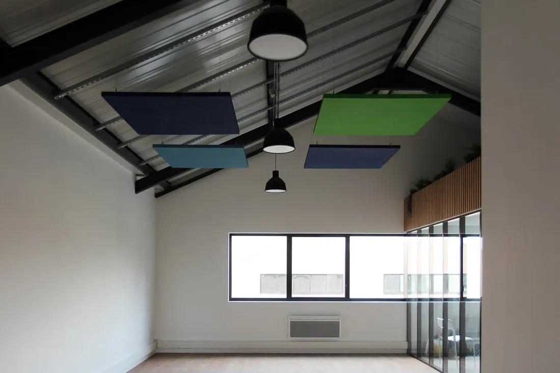 Plafond cathédrale avec panneaux acoustiques bleus et verts et suspensions noires